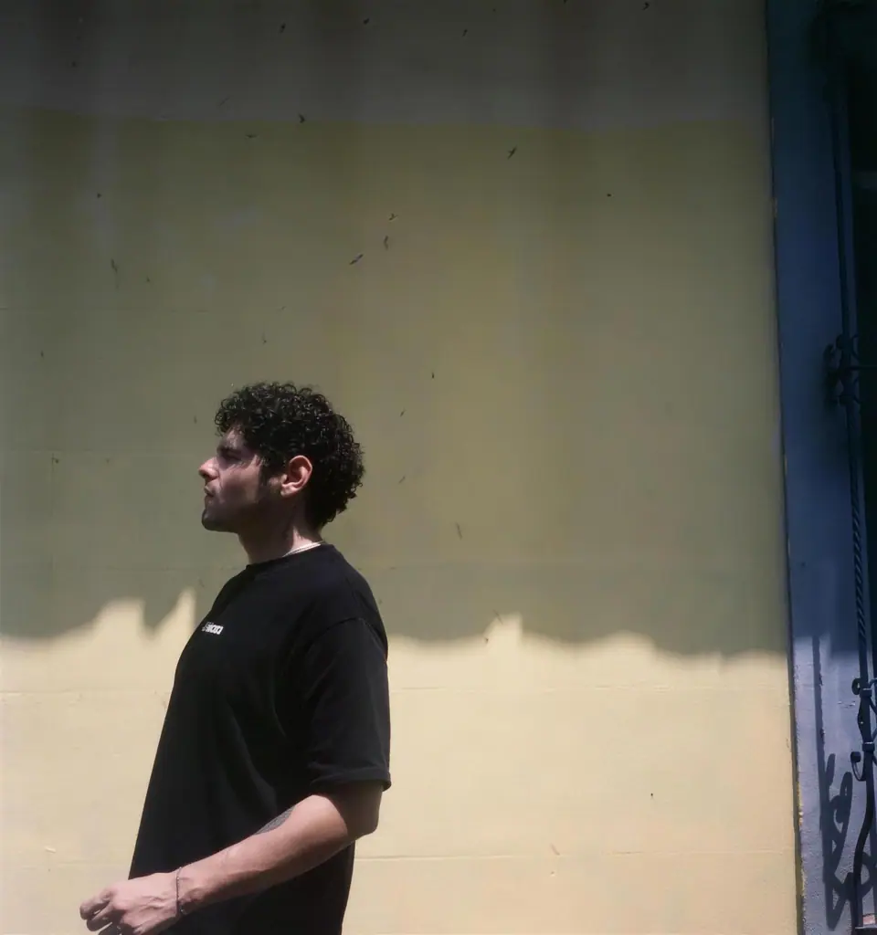 Juanito State im Profil vor einer cremefarbenen Wand, Cali